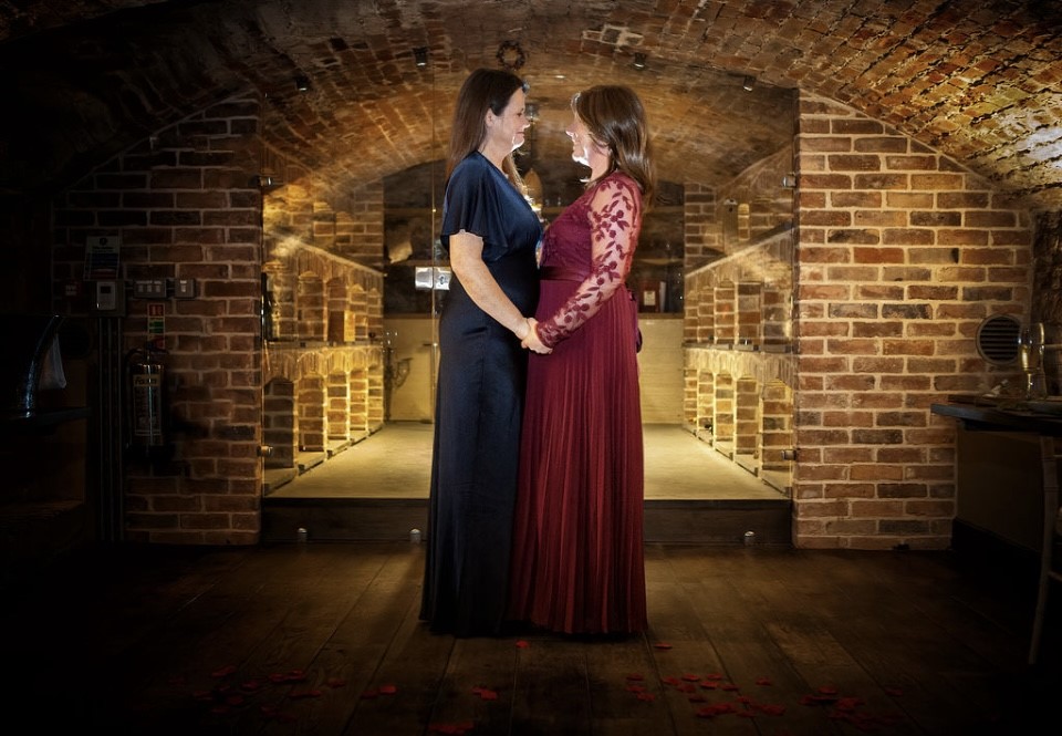Female Wedding couple holding hands looking at each other at the vaulted cellar